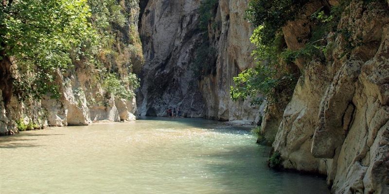 The Acheron river running green between tall rock walls covered in trees