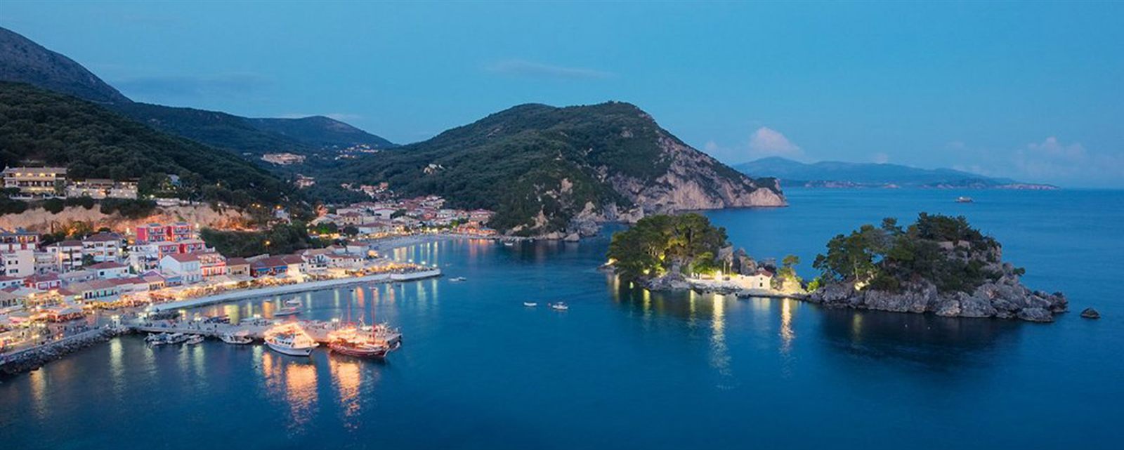 Parga harbour and the Panagia islet at dusk, with the town lights reflected in the water