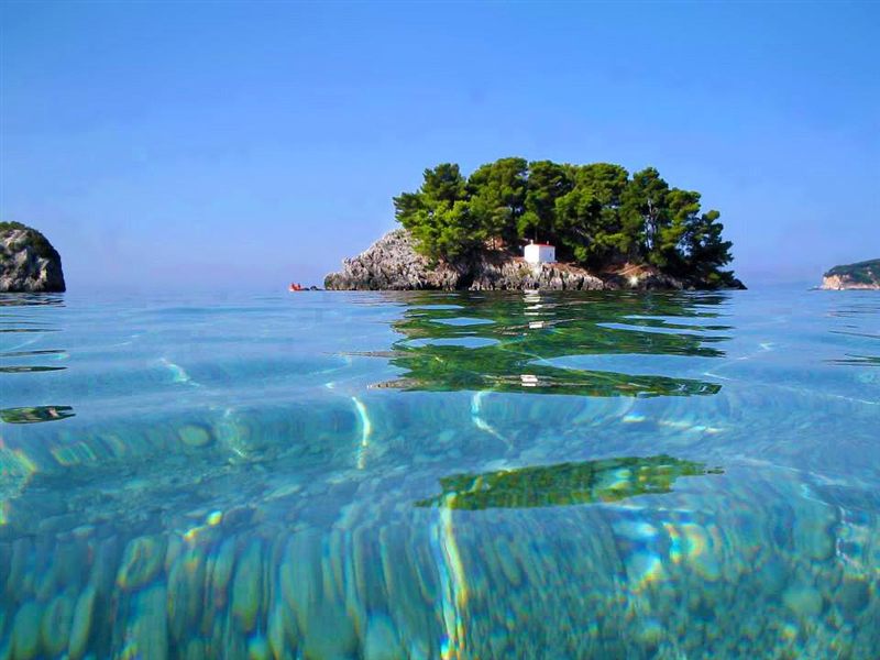 The wooded Panagia islet with its small white chapel, seen from the clear water